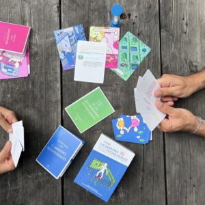 Illustration de la formation "Comment communiquer sur le changement climatique et la perte de biodiversité". Deux personnes jouent à un jeu de carte pédagogique sur les barrières psychologiques.